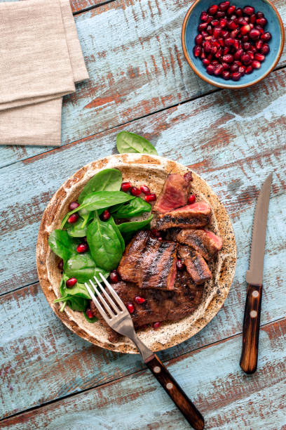 istock Beef steak grilled with spinach leaves and pomegranate in a plate on a wooden table 657146332