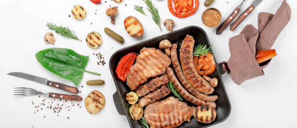 istock steak and sausage cooked on a grill with grilled vegetables in a cast iron pan on a white background 657147894