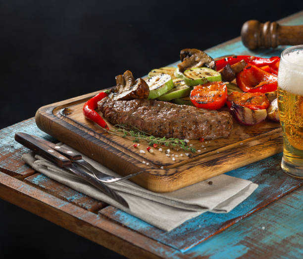 istock Steak grill with grilled vegetables on wooden table with light beer 657148110