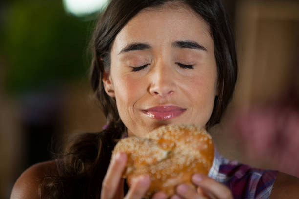 sonriente mujer que huele a pan en el mostrador - smelling bread bakery women fotografías e imágenes de stock