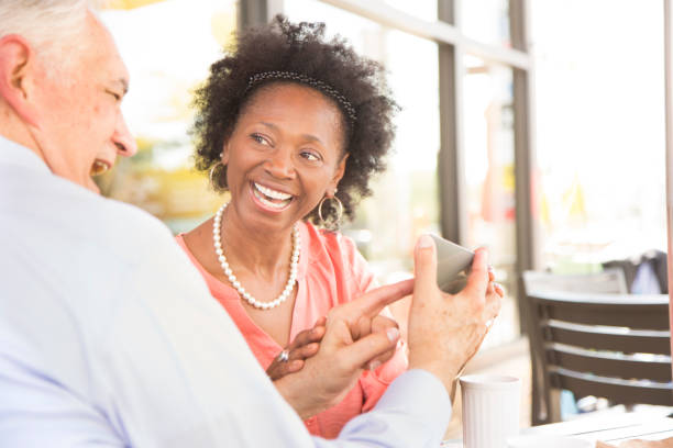 istock Mixed race, senior adult couple using smart phone at cafe. 657154178