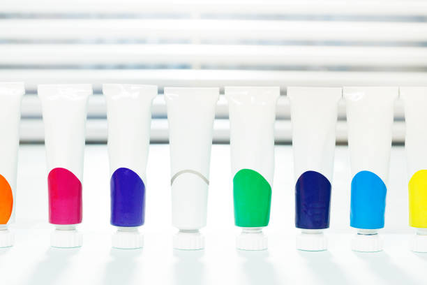 Close-up picture of small tubes of acrylic paint with copy-space, standing in a row on the table