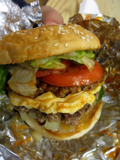 istock Close up of hands holding hamburger wrapped in tinfoil 657163500