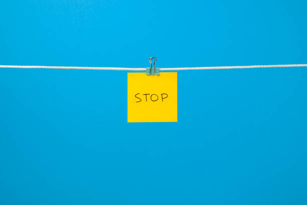 istock Yellow paper sheet on the string with text Stop over colorful background 657163750