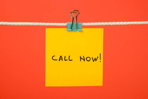 istock Yellow paper note on clothesline with text Call Now! over colorful background 657163780