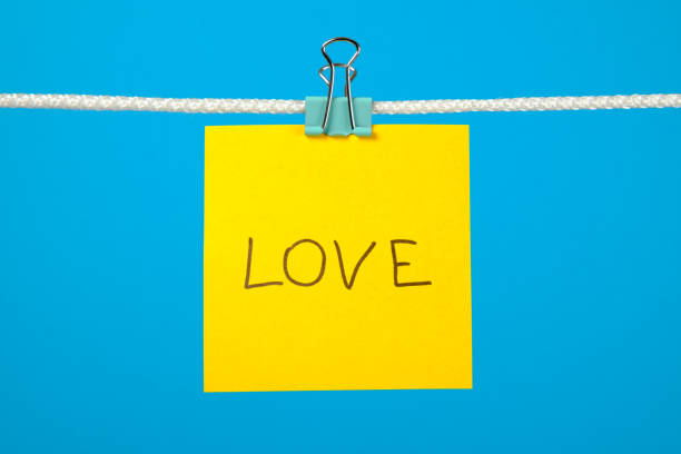 istock Yellow paper note on clothesline with text Love over colorful background 657163786