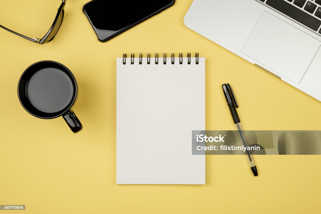 Tabela de mesa de escritório moderna com laptop, página do caderno em branco para entrada de texto no meio e outras fontes. Vista superior, plana leiga - Foto de stock de Caderno de Anotação royalty-free