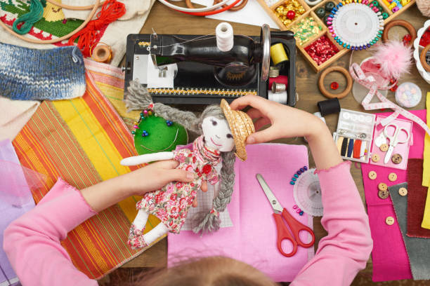 istock girl sews doll clothes, top view, sewing accessories top view, seamstress workplace, many object for needlework, handmade and handicraft 657175146