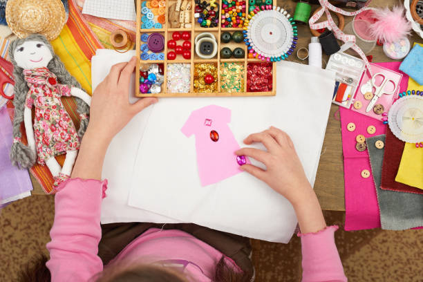 istock girl sews doll clothes, top view, sewing accessories top view, seamstress workplace, many object for needlework, handmade and handicraft 657177724