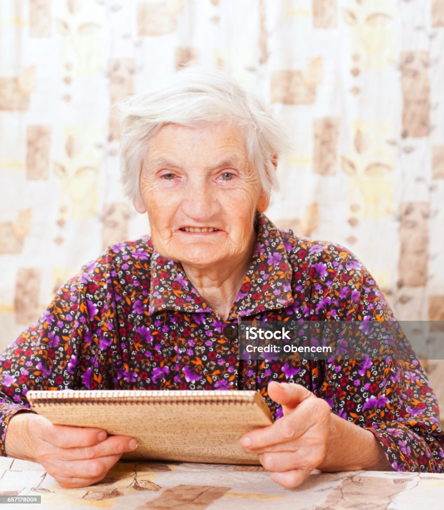 Elderly happy woman read something from the book Elderly happy woman read something Adult Stock Photo