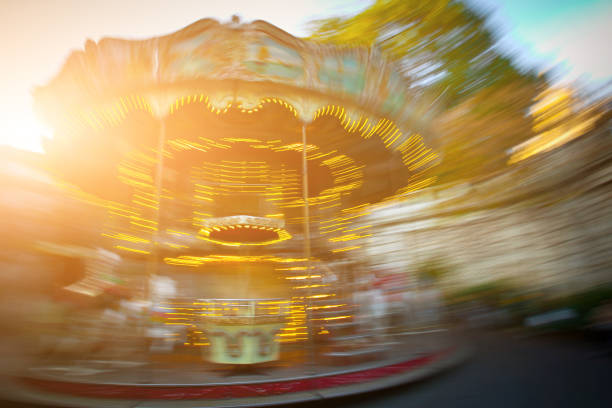 Abstract background. Rotating classic style carousel on Montmartre in backlit evening sunset sunbeam . Motion blur effect defocusing filter applied, with vintage camera lense look.