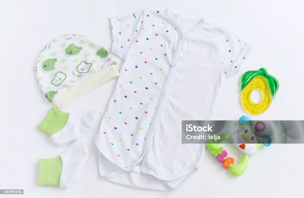 newborn baby patterned bodysuit with hat, knitwear booties and teether newborn baby set of clothes: patterned bodysuit with hat, knitwear booties and teether on white background Newborn Stock Photo