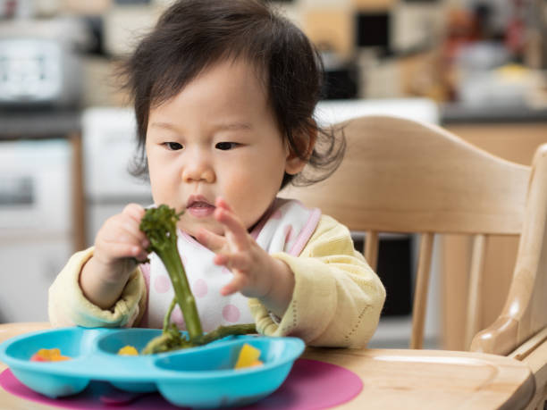 istock baby girl eating vegetable first time 657203650