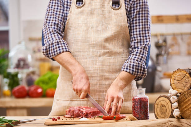 istock Butcher cutting pork, beef or mutton steak meat on kitchen with vegetables background 657206910