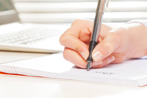 istock Female hand with fountain pen writing on notebook 657219658