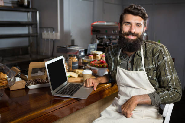 istock Smiling male staff using laptop at counter in bakery shop 657252922
