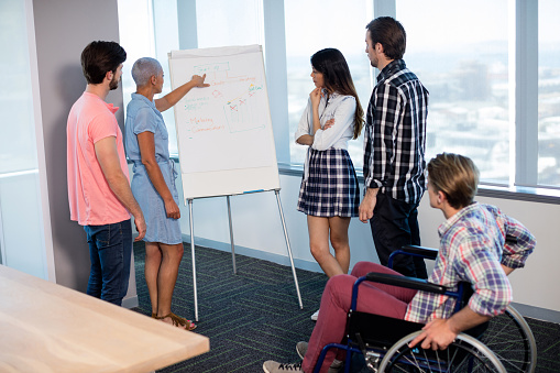 Woman giving presentation to her colleagues in office