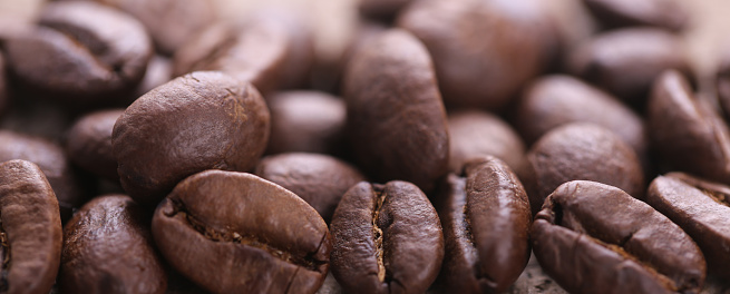 Some coffee beans are on the wooden background.