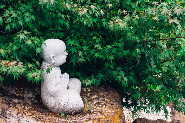 istock Profile of a small praying Buddha statue under the tree in nature 657273530