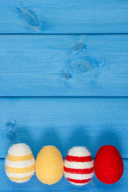 oeufs de pâques enveloppé string de laine sur des planches en bois bleu, espace de copie pour le texte, décoration pour pâques - easter bonnets photos photos et images de collection