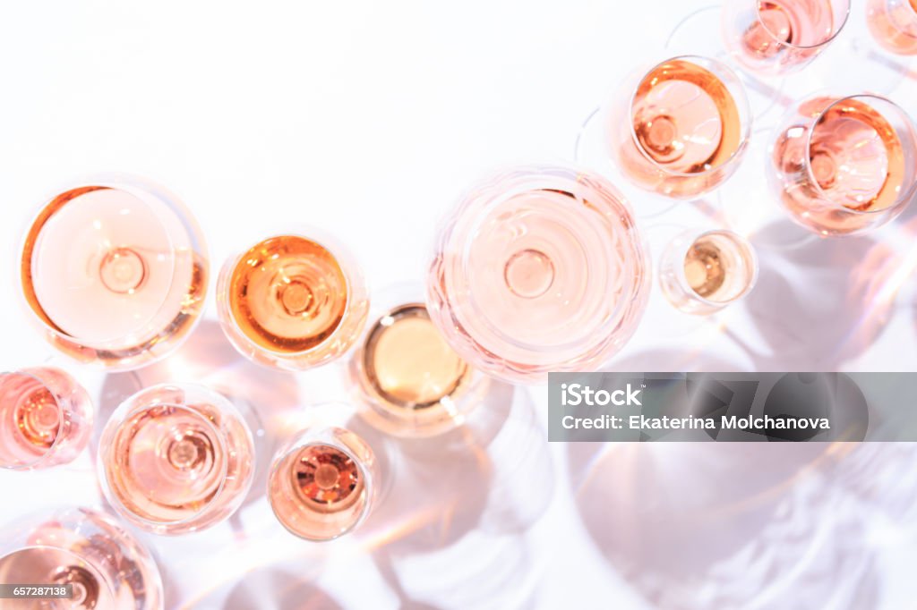 Many glasses of rose wine at wine tasting. Concept of rose wine and variety Many glasses of rose wine at wine tasting. Concept of rose wine and variety. White background. Top view, flat lay design. Direct sunlight. Toned image. Rosé Wine Stock Photo