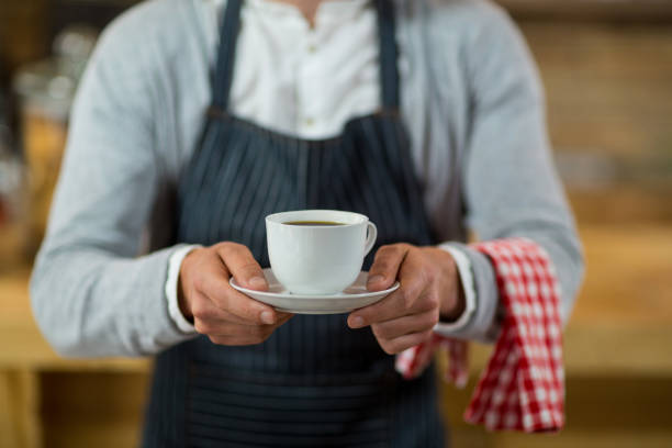 istock Mid-section of waiter standing with cup of coffee 657287200
