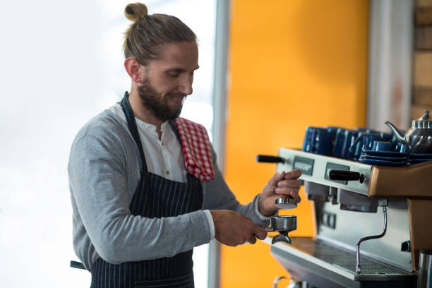 istock Waiter using a tamper to press ground coffee into a portafilter 657287536