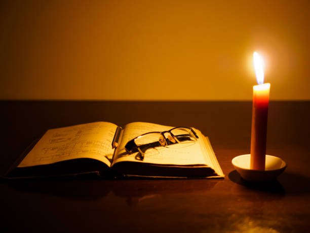 istock opened book on a wooden table lighted candle and glasses 657299144