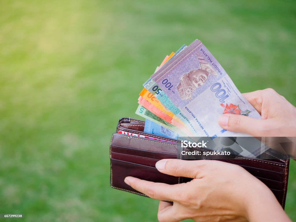 Hands taking out money malaysia ringgit from wallet on the green grass field Women Hands taking out money malaysia ringgit from wallet on the green grass field Adult Stock Photo