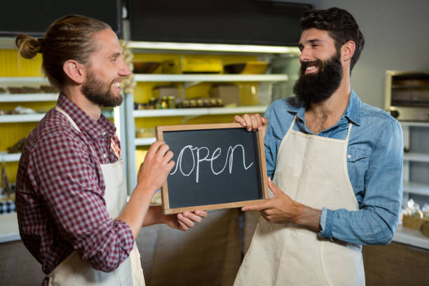 istock Smiling male staffs holding a open sign 657307590