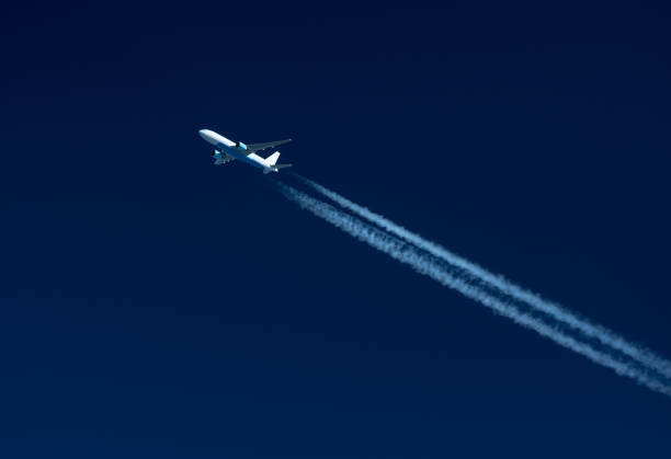 istock Airplane Leaving Contrail against dark Blue sky 657314854
