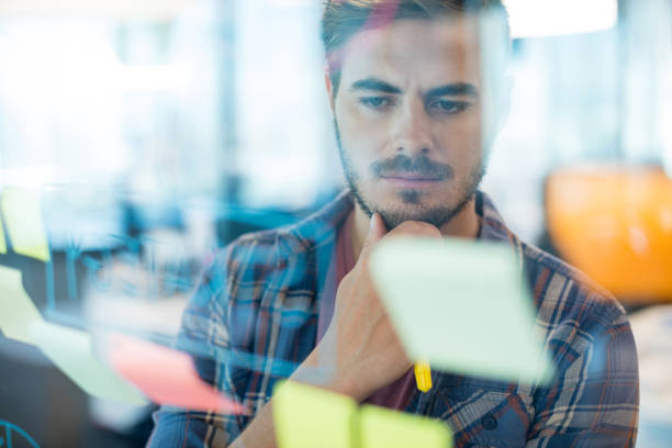 istock Thoughtful man reading sticky notes on the glass wall 657317368