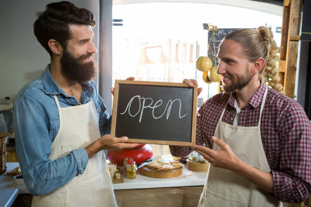istock Smiling male staffs holding a open sign 657324336