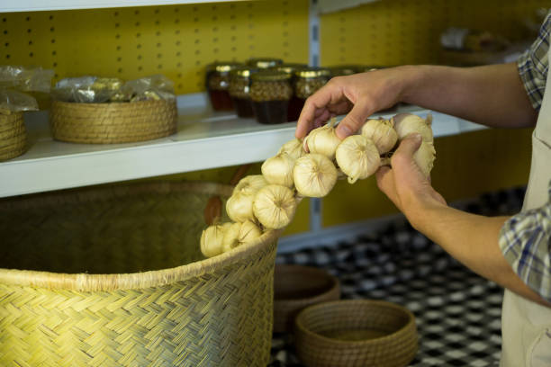 Mid-section of staff putting garlic in wicker basket in market
