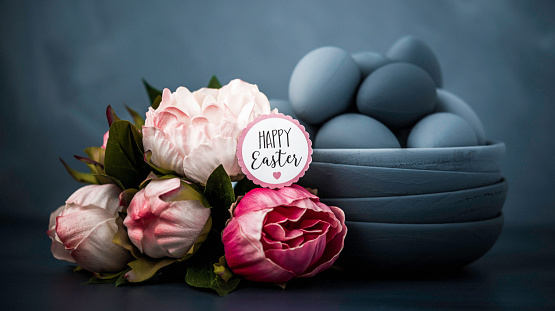 Dark toned Easter still life with peony bouquet and hand painted ombre eggs and bowls.