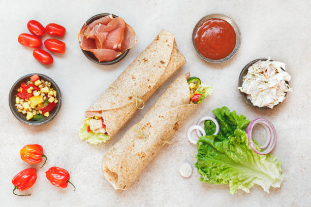 Tortilla wrap sandwiches with various fillings Wholemeal tortilla wrap with various fillings on rustic surface. Top view, blank space tortilla flatbread stock pictures, royalty-free photos & images