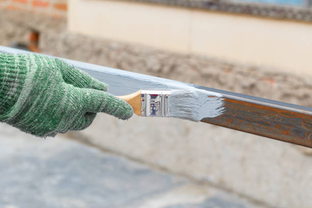 istock Hand in green rag glove paint brush steel post in gray anti rust paint.  Half - painted surface. Smear of paint brush 657348004