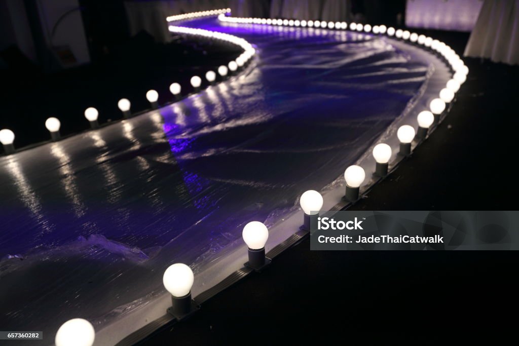 Empty Runway Fashion Show with Ball glowing lighting along walk way with plastic white floor in the dark Fashion Show Stock Photo