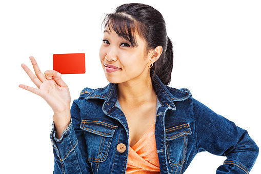 Photo of an attractive young Asian woman holding a blank red credit card (or gift card, etc.) with a smile on her face; isolated on white