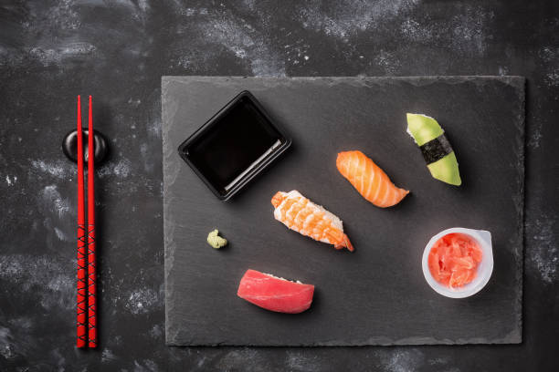 istock Various sushi and rolls on slate plate and black stone table with chopsticks, wasabi., ginger and soya sauce. Japanese cuisine 657377344