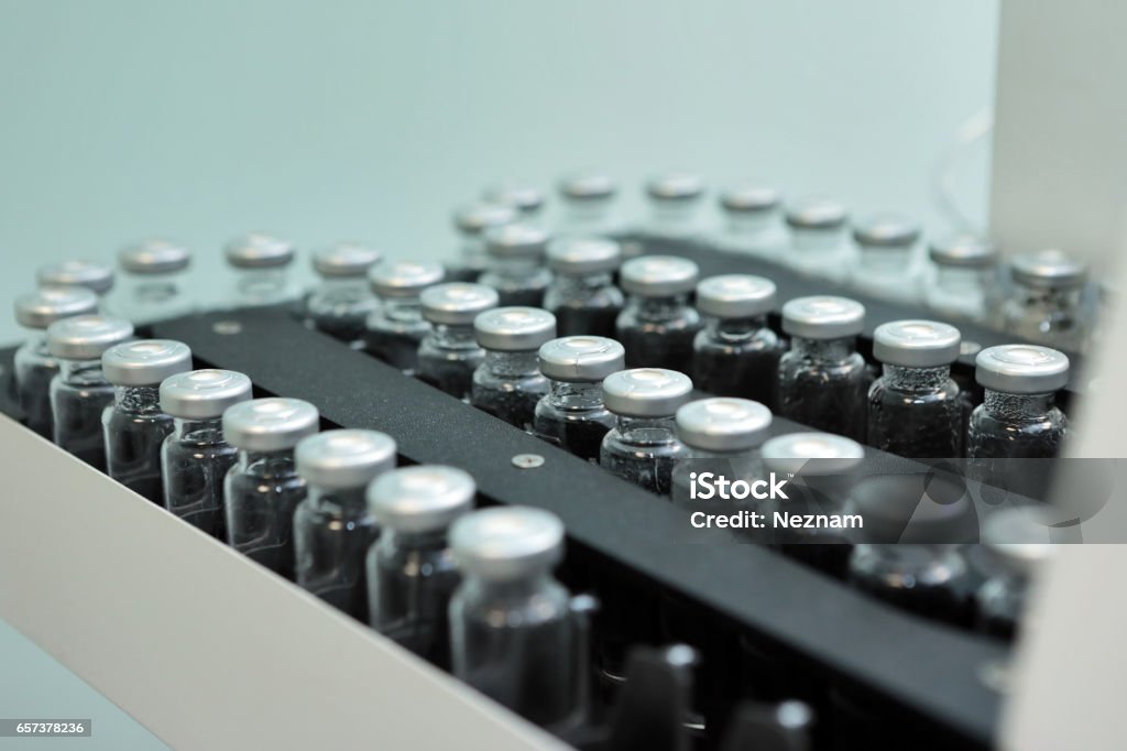 Sterile capsules for injection. Bottles on the bottling line of the pharmaceutical plant. Machine after checking sterile liquids. Interferon, nasoferon. Sterile bottles and ampoules on the dispensing line. Sealed ampoules with medicine. Manufacturing Stock Photo