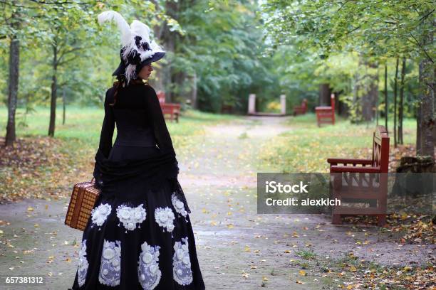 Girl In Retro Dress 18th Century With Valise In Park Stock Photo - Download Image Now