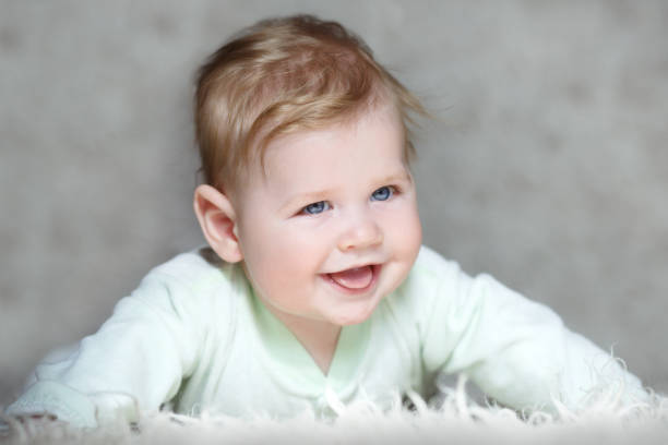 istock Laughing baby lying on his stomach on a gray background 657384820