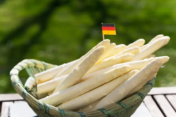Asparagus, white asparagus and potatoes in the basket, german flag
