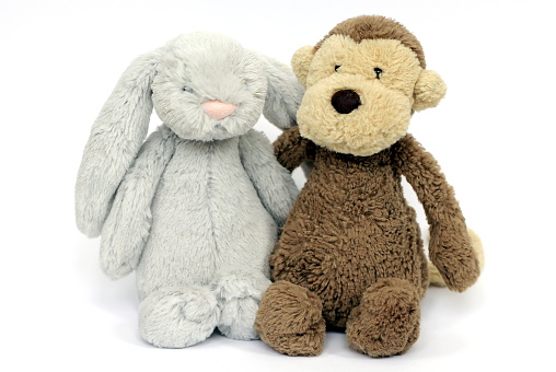 A fluffy grey rabbit and soft brown monkey toy for a baby or child