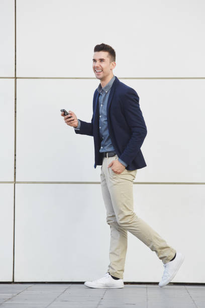 istock confident laughing business man walking with smart phone 657396294