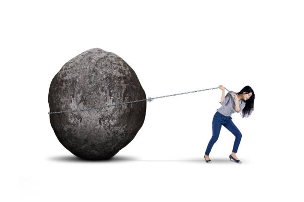 Female entrepreneur pulling big stone on studio Young female entrepreneur is pulling big stone with a chain, isolated on white background boulder rock photos stock pictures, royalty-free photos & images