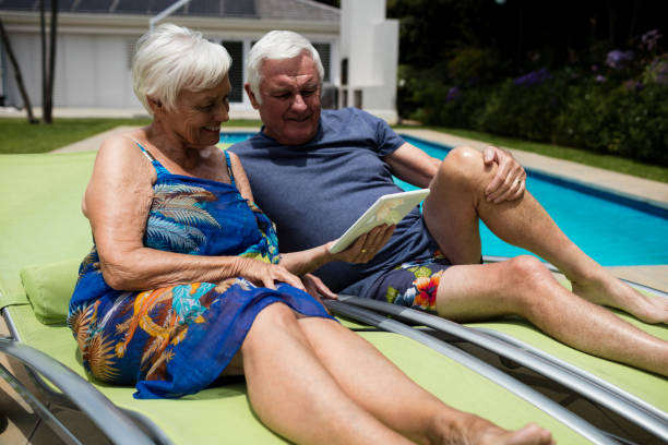 pareja senior en tableta digital en silla de salón - outdoor chair beach chair sarong fotografías e imágenes de stock