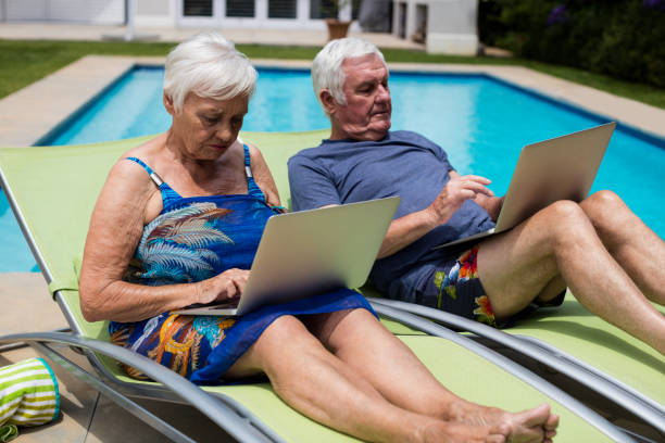 senior pareja con laptop en butaca - outdoor chair beach chair sarong fotografías e imágenes de stock