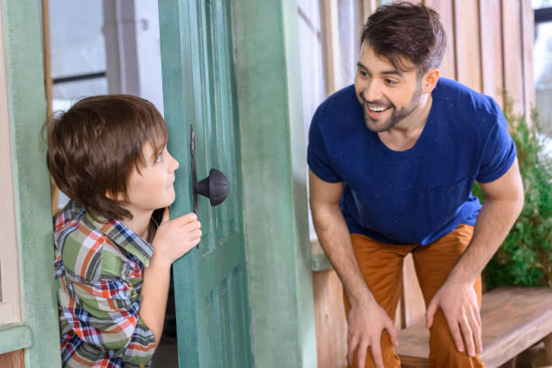 istock side view of smiling father and son playing hide and seek at home 657408028